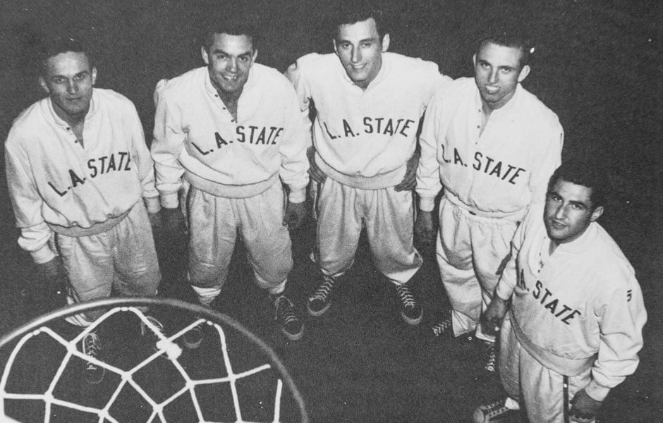 A team photo showcasing 5 members of the team under the basketball rim.